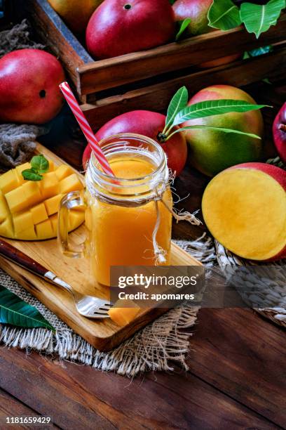 mango smoothie saft und obst un trinkglas auf holztisch in rustikaler küche - mango juice stock-fotos und bilder