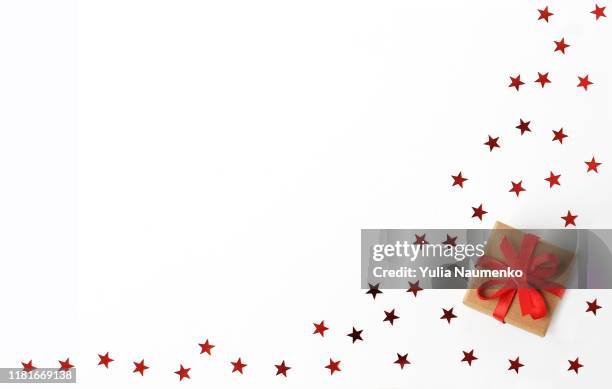 christmas decoration isolated white. gift box with with red ribbon on a white background with stars confetti. top view, copy space. - red tops stock pictures, royalty-free photos & images