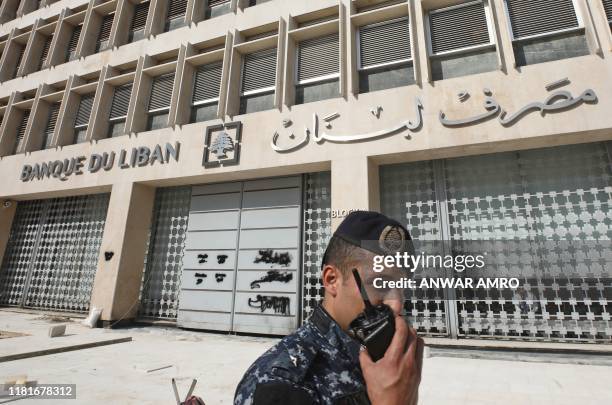 Member of the Lebanese security forces stands at the entrance of the Central Bank after anti-government protesters broke down a construction barrier...