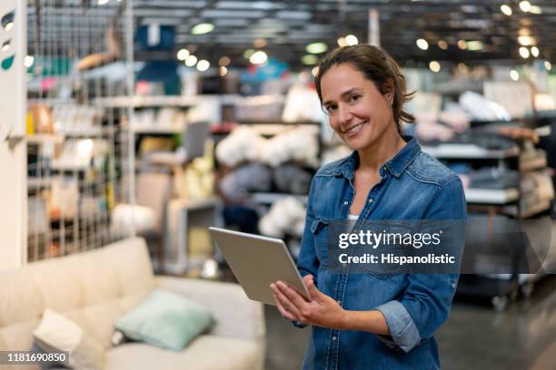 happy interior designer at a home furniture store holding a tablet while smiling at camera - sales assistant furniture stock pictures, royalty-free photos & images