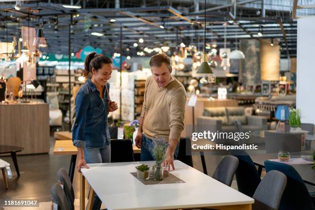 couple choosing a dining table for their home at a furniture store both smiling - loja de móveis imagens e fotografias de stock