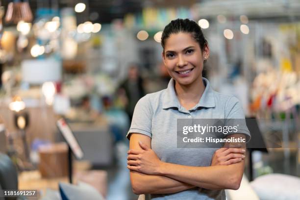 confident female manager of a furniture store looking at camera smiling with arms crossed - retail assistant stock pictures, royalty-free photos & images