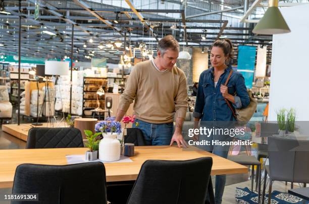 mid adult couple choosing dining tables at a furniture store - furniture shop stock pictures, royalty-free photos & images