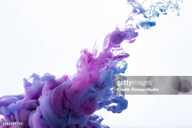 colorful ink swirling in water. - viola colore foto e immagini stock