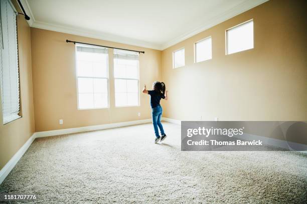 young girl dancing in empty room of new house during move - camera bambino foto e immagini stock