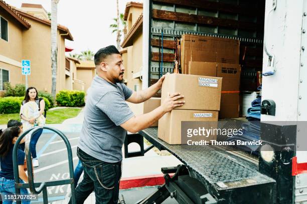 father loading boxes into moving truck during family move - camión de las mudanzas fotografías e imágenes de stock