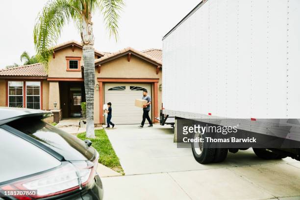 Son helping father carry items in new home from moving truck