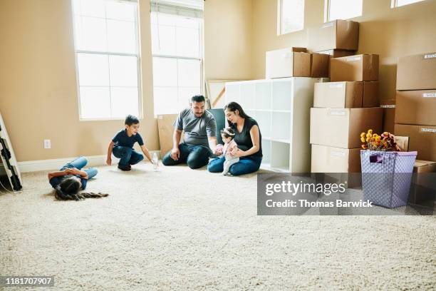 family sitting on floor of living room of new home during move in day - 體力活動 個照片及圖片檔