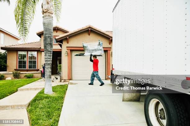 mover carrying furniture from moving truck into home - moving truck stock pictures, royalty-free photos & images