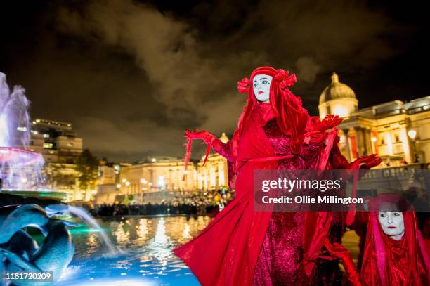 Members of the surrealist Extinction Rebellion environmental activist performance art group The Red Brigade pose at Trafalgar Square as thousands...