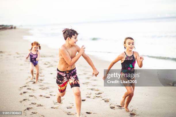 drie kinderen hebben een race langs een strand - beach florida family stockfoto's en -beelden