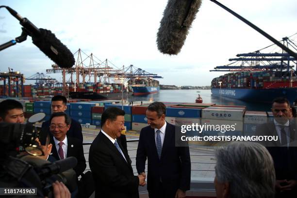 President of the Republic of China Xi Jinping and Greek Prime Minister Kyriakos Mitsotakis shake hands as they visit the cargo terminal of Chinese...