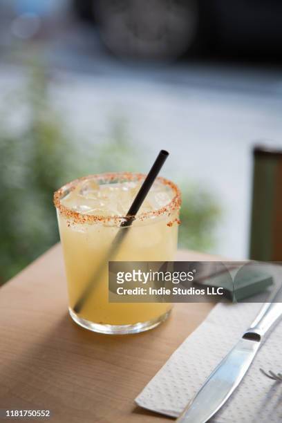 a spicy margarita sits on the edge of a table with street in background - vertical - margarita stockfoto's en -beelden
