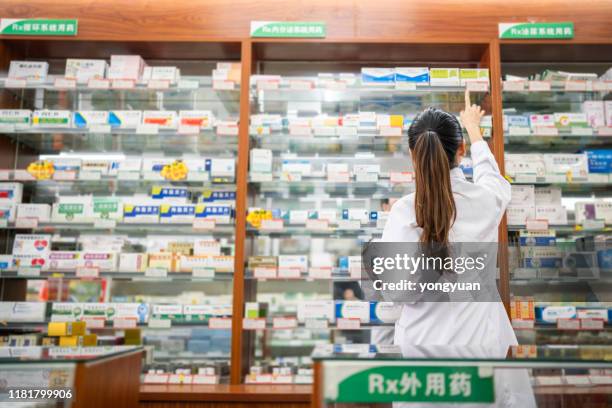 female pharmacist working in a drug store - doctor arms raised stock pictures, royalty-free photos & images