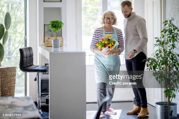 sonriendo mujer mayor con un montón de flores recibidas de un hombre joven - old woman young man fotografías e imágenes de stock