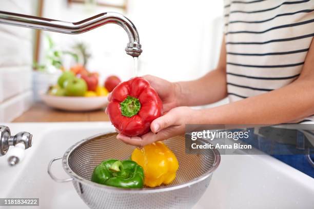 woman washing colorful peppers. rzeszow, poland - pepper spray stockfoto's en -beelden