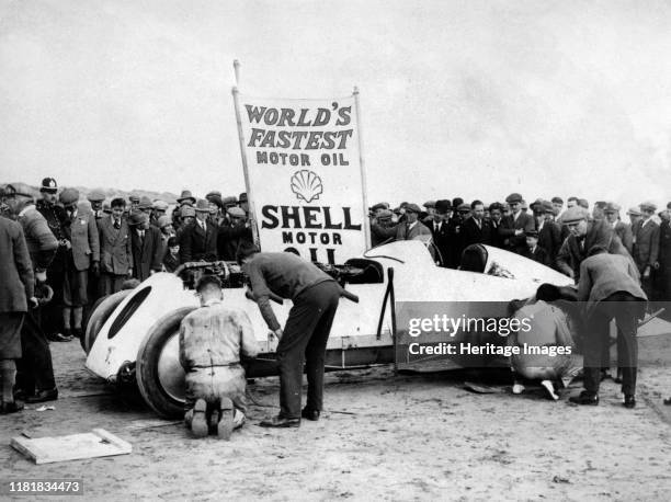 With Parry Thomas, having wheel changed at Pendine sands 1926. Creator: Unknown.
