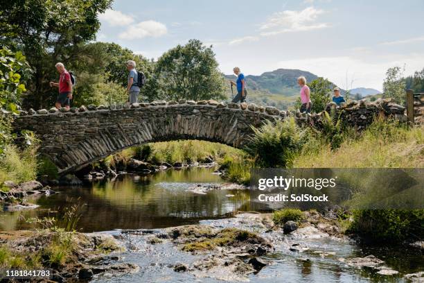 senior friends überqueren steinbrücke. - lake district stock-fotos und bilder