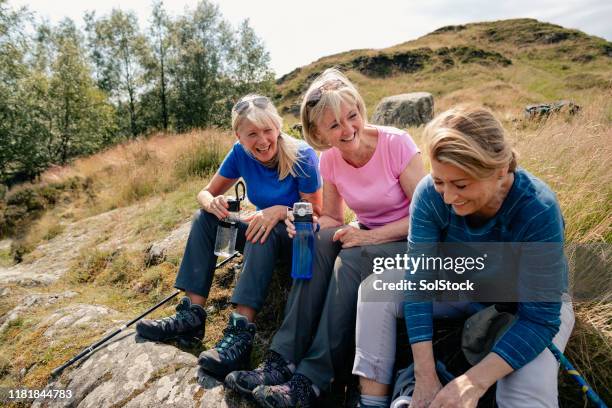 group of senior women sharing a few jokes during refreshment break - woman on walking in countryside stock pictures, royalty-free photos & images