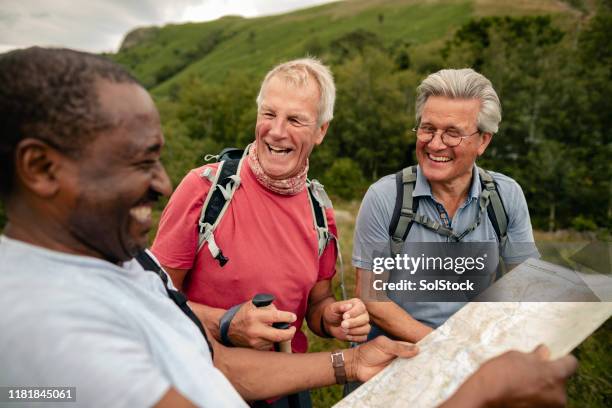 senior friends lachen und lächelnd blick auf die karte - orientierungslauf landkarte gruppe stock-fotos und bilder