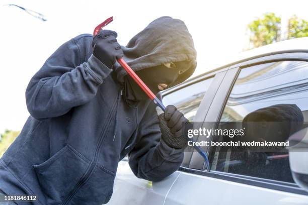 car theft - thief trying to break into the vehicle - anonymous mask stockfoto's en -beelden