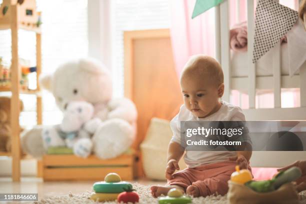 bébé adorable s'asseyant à l'étage avec des jouets - chambre bébé photos et images de collection