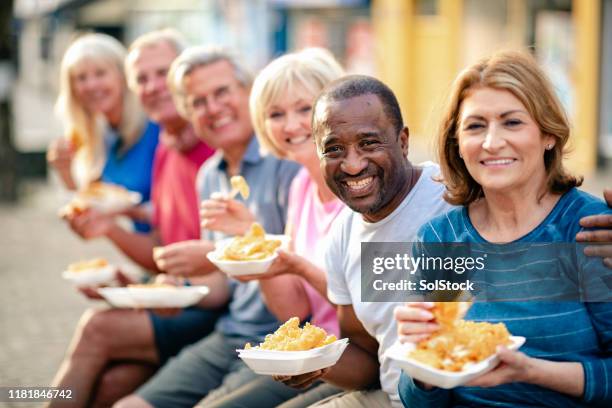 senior man glimlachend het houden van fish and chips - fish chips stockfoto's en -beelden