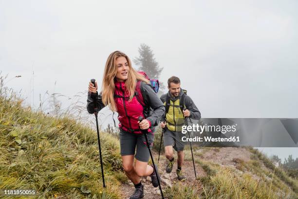 young couple on a hiking trip in the mountains, herzogstand, bavaria, germany - couple hiking stock-fotos und bilder