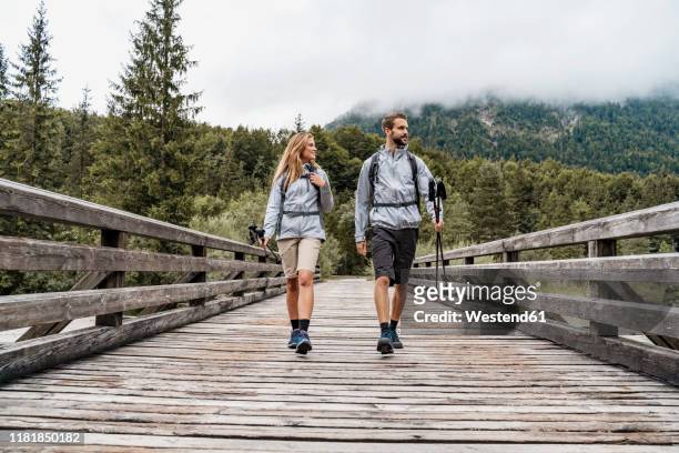 young couple on a hiking trip walking on wooden bridge, vorderriss, bavaria, germany - naderen stockfoto's en -beelden