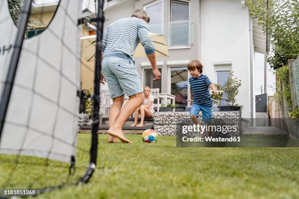 father and son playing football in garden - lawn mover stock pictures, royalty-free photos & images