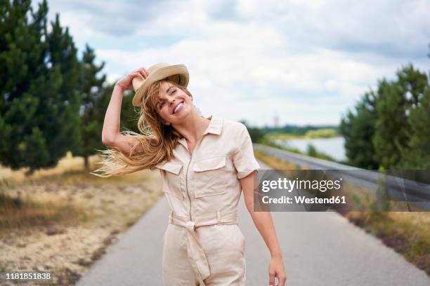 smiling woman on rural road at the lakeside - jumpsuit 個照片及圖片檔