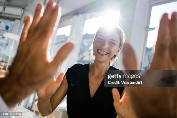 blond businesswoman high fiving a colleague - esprimere a gesti foto e immagini stock