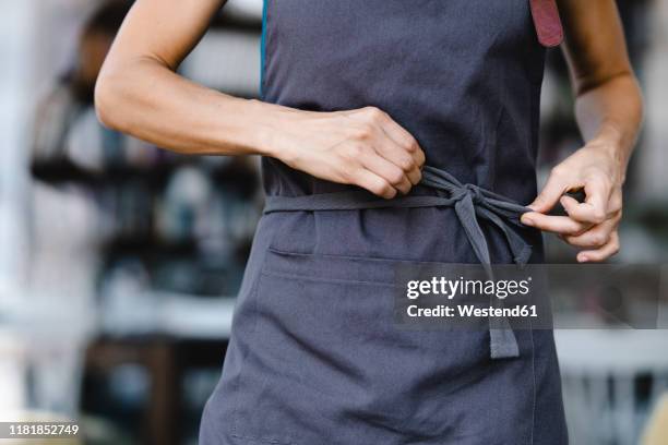 woman tying her apron before work - tablier photos et images de collection