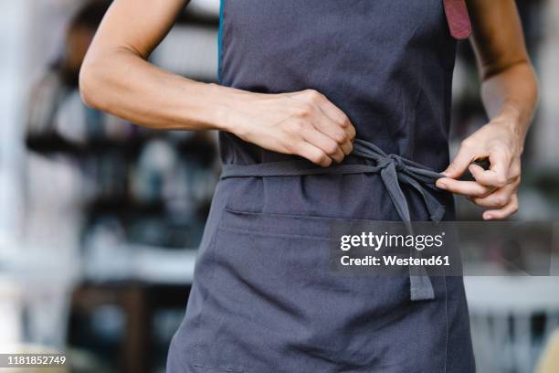 woman tying her apron before work - apron stockfoto's en -beelden