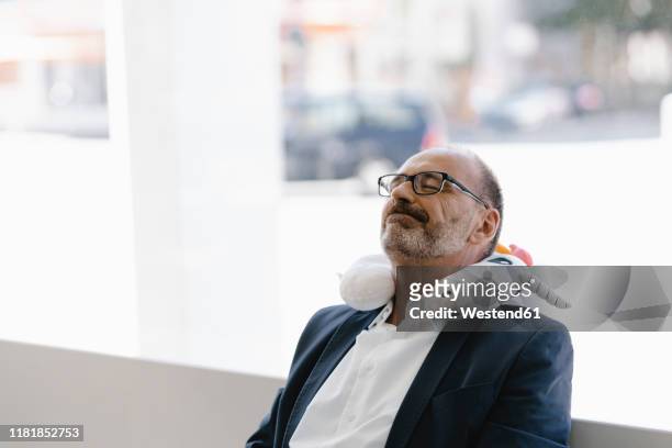 businessman taking a nap, with a unicorn pillow around his neck - nickerchen stock-fotos und bilder