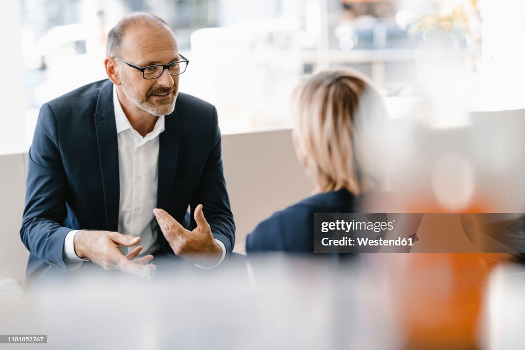 Businessman and woman having a meeting in a coffee shop, discussing work