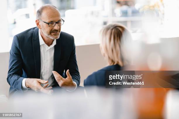 businessman and woman having a meeting in a coffee shop, discussing work - discussion foto e immagini stock