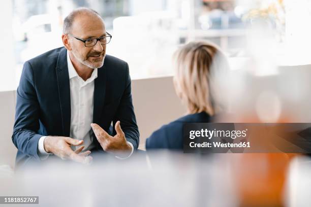 businessman and woman having a meeting in a coffee shop, discussing work - explaining stock pictures, royalty-free photos & images