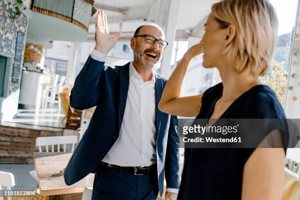 business people high fiving in a coffee shop - business high five stock pictures, royalty-free photos & images