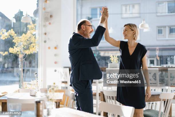 successful businessman and woman high-fiving in a coffee shop - two executive man coffee shop stockfoto's en -beelden