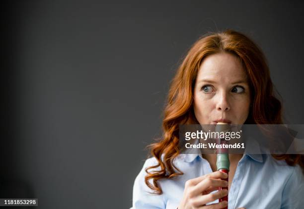 portrait of redheaded woman playing recorder - blockflöte stock-fotos und bilder