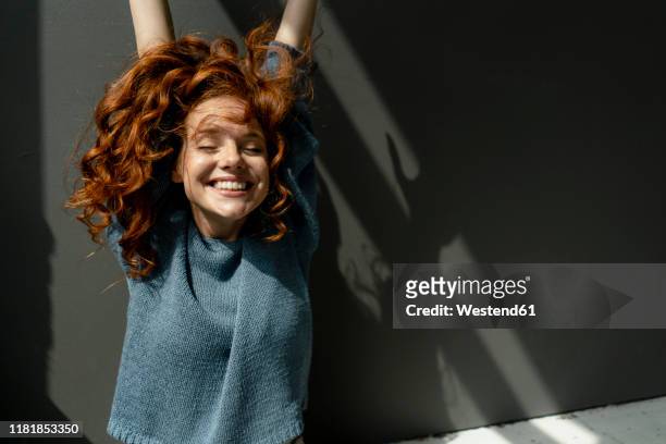 portrait of happy redheaded woman with eyes closed raising hands - woman happy raised arms closed eyes stock pictures, royalty-free photos & images