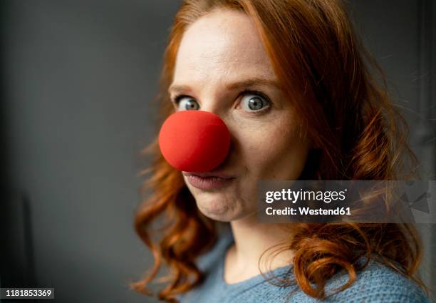 portrait of redheaded woman with clown's nose - payaso fotografías e imágenes de stock