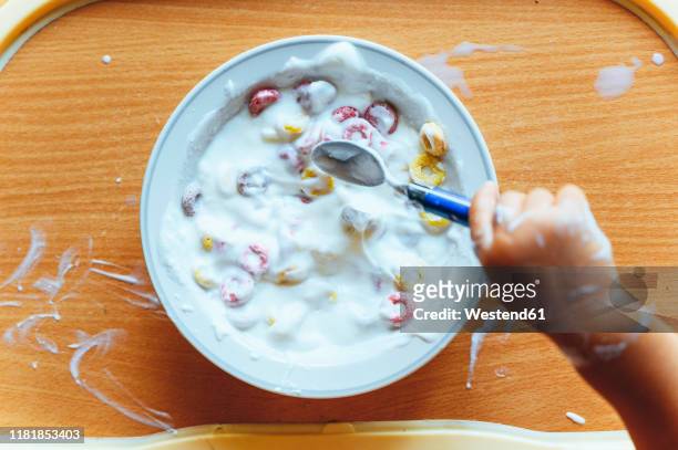 little boy eating yogurt at home, from above - plate in hand stockfoto's en -beelden