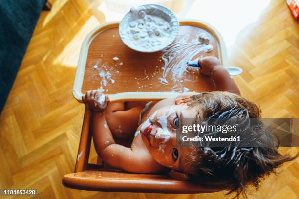 little boy eating breakfast at home, sitting in high chair, from above - baby eating food stock pictures, royalty-free photos & images