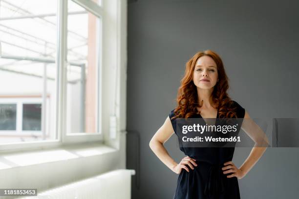 portrait of redheaded businesswoman in a loft - mano sobre la cadera fotografías e imágenes de stock