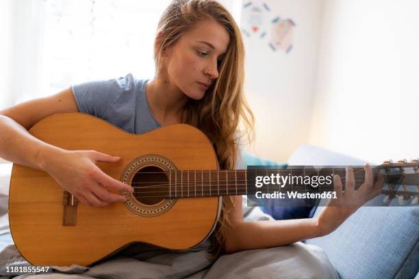 young woman at home playing guitar with damaged string - musical instrument string stock pictures, royalty-free photos & images