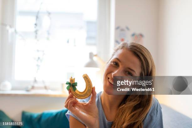 portrait of smiling young woman at home holding horseshoe - lucky charms stockfoto's en -beelden