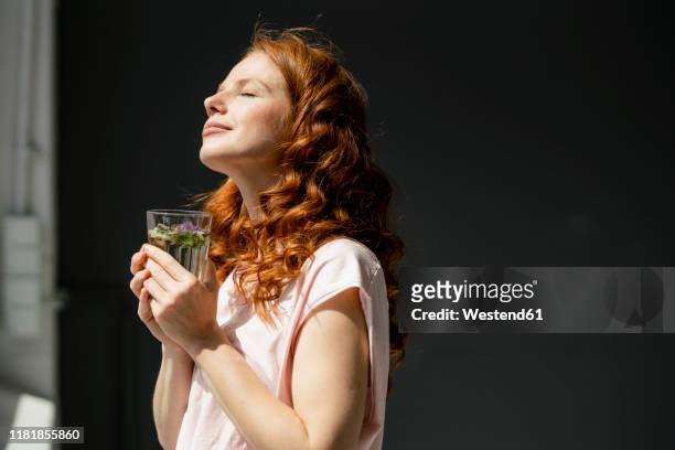 redheaded woman enjoying sunlight - drink stock-fotos und bilder