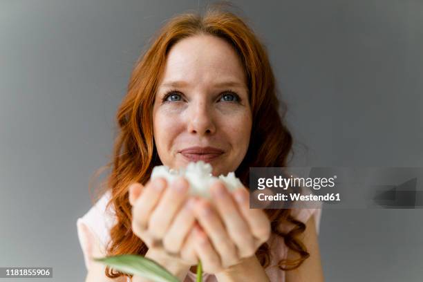 portrait of redheaded woman smelling white peony - long nose foto e immagini stock